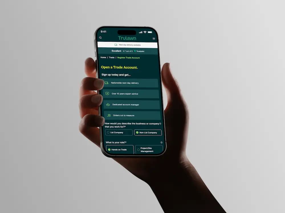 a hand holding a phone with trulawn website open